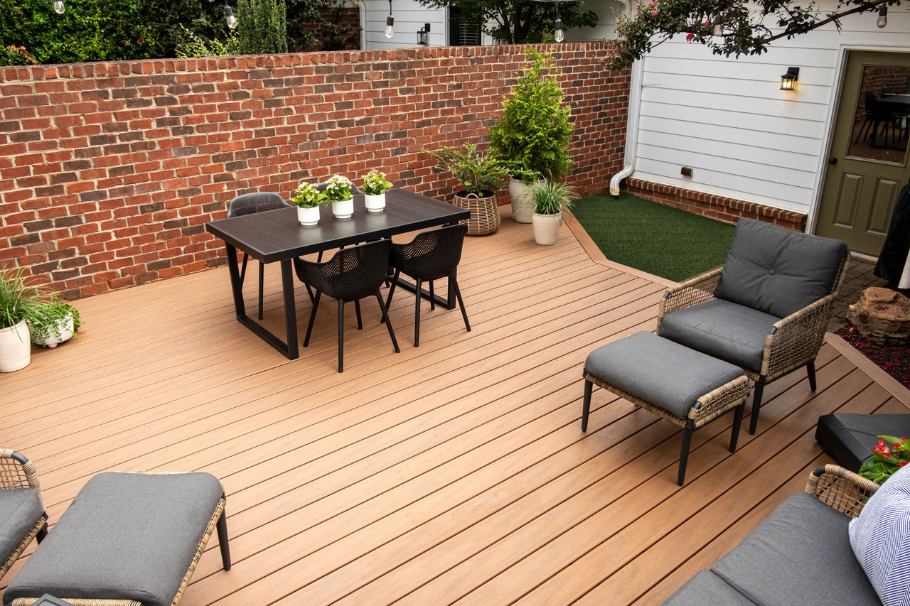 Trex Transcend Lineage decking in Jasper color in a backyard with brick accents, patio furniture and plants